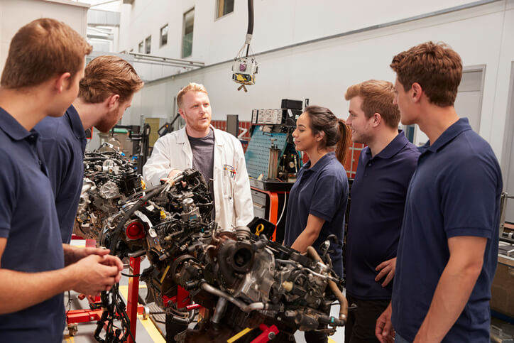 Apprentices deciding on auto careers while speaking to their lecturer.