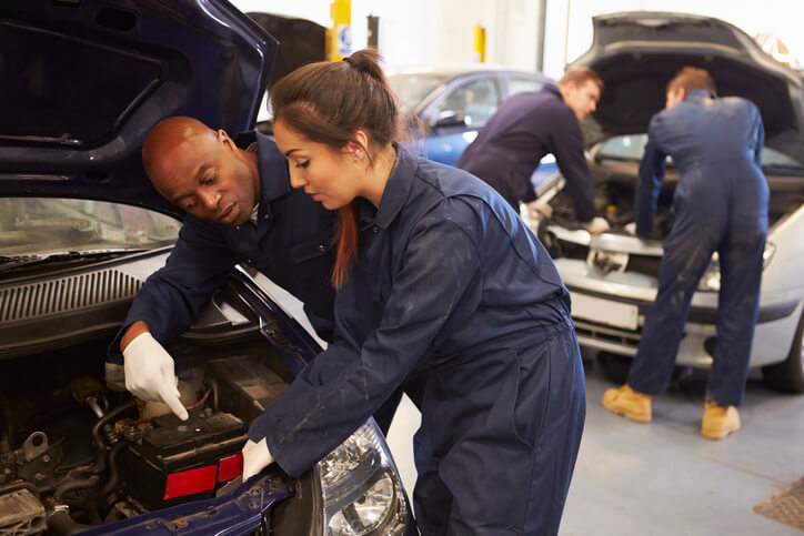 A teacher explaining something to his student in an automotive school