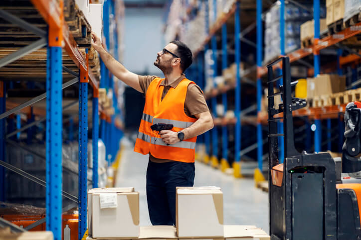 Dispatcher holds a scanner in hands checking boxes in a warehouse after auto parts training.