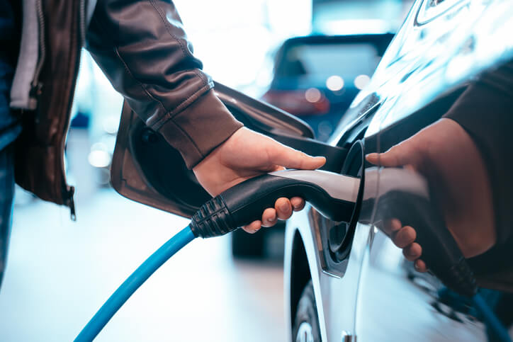 utomotive training grad stands by an electric vehicle as it charges