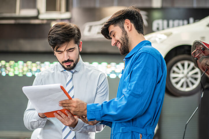 A service advisor explaining costs to a customer in an auto shop after hybrid and electrical mechanic training