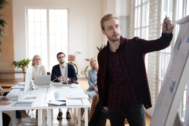 A startup leader presenting charts to his team in a meeting room after automotive business manager training