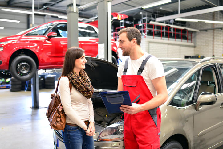 Student in automotive school talking to a client in the shop