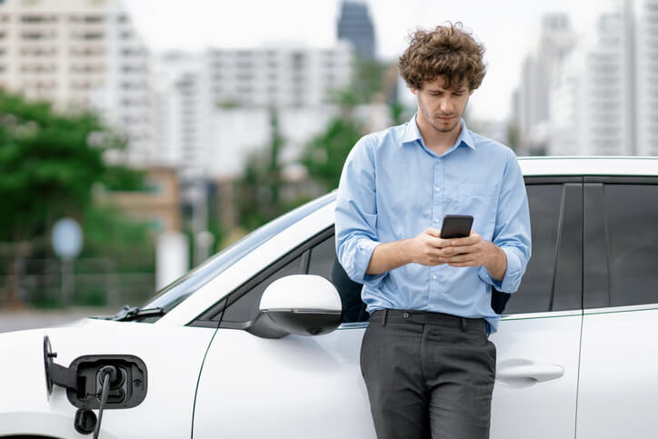 A businessman talking on the phone while charging his EV after hybrid and electrical mechanic training