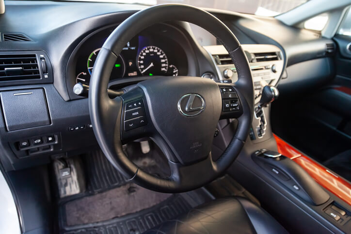 An interior view of a Lexus vehicle focusing on the steering wheel and dashboard as seen in auto mechanic school.