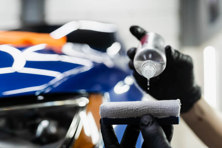 An auto detailing training student applying a lubricant to a cloth before application