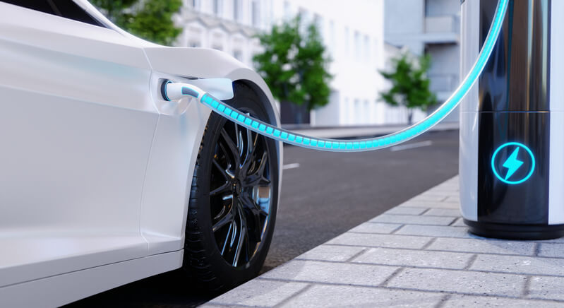 A student in hybrid and electrical mechanic training charging an EV