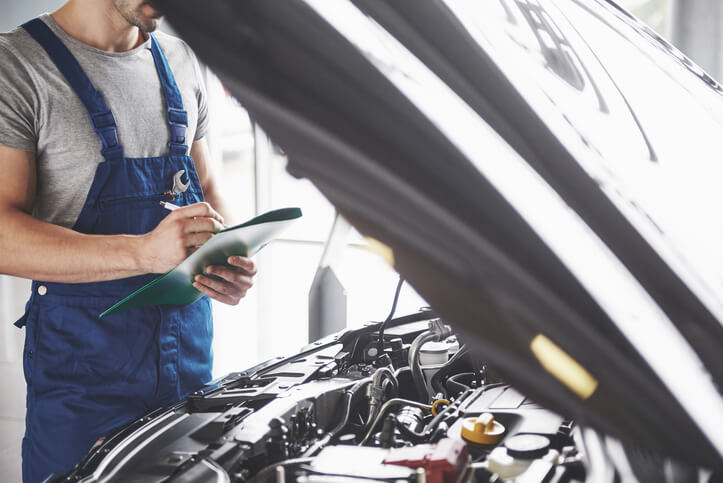 An auto body estimator checking the engine of a vehicle after completing his auto body estimating training