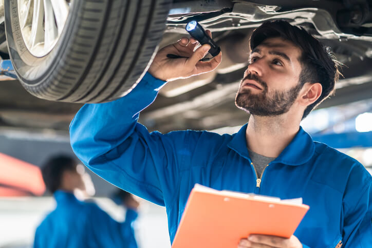 A mechanic inspecting the frame of a vehicle after auto body training