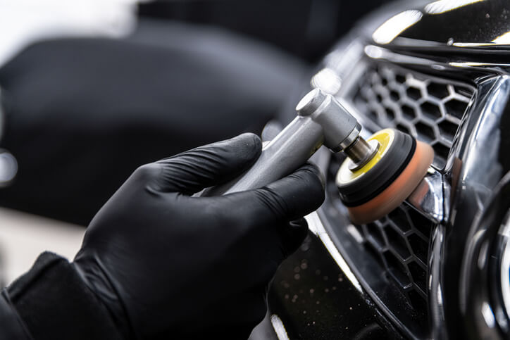 A professional auto detailer polishing a car’s chrome after completing auto detailing training