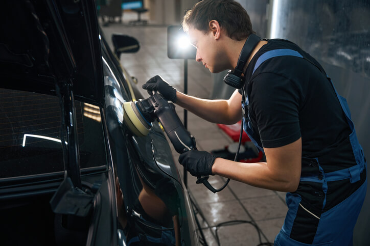 Male auto detailing professional working on a vehicle in his shop after completing his auto detailing training