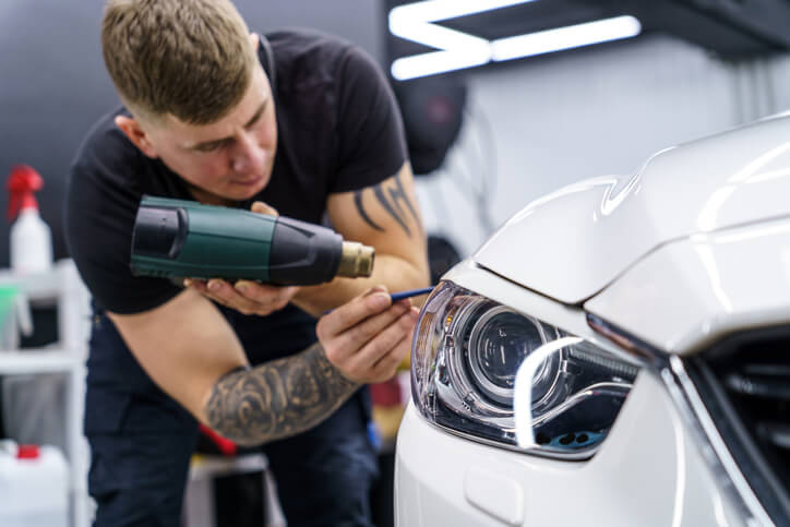 A male auto detailer polishing the headlight of a car after completing auto detailing training