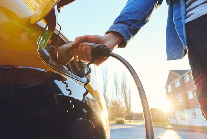 An automotive training grad plugging in an electric vehicle