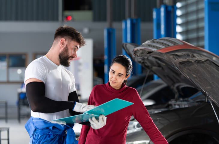 A collision estimating training grad speaking with a customer 