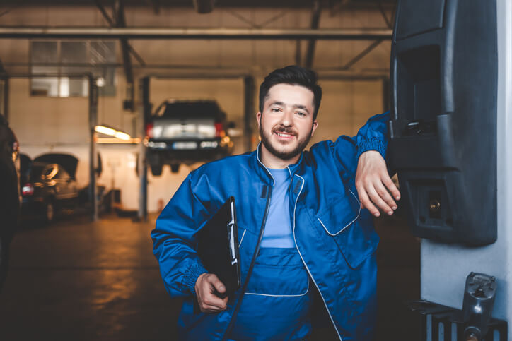 A smiling auto shop foreman in a garage after completing auto mechanic school