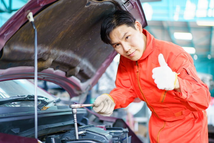 A focused shop foreman examining a vehicle after graduating from auto mechanic school