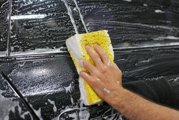 An auto detailing professional cleaning a car’s exterior after completing his auto detailing training