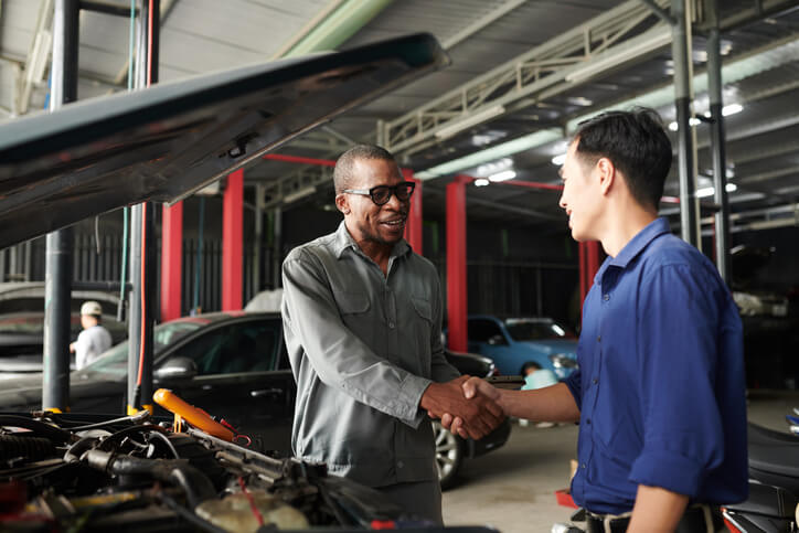 A male engine technician interacting with a colleague after graduating from auto mechanic school