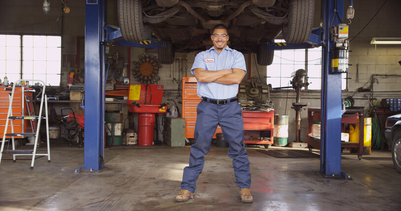 An auto mechanic training grad standing in an auto shop