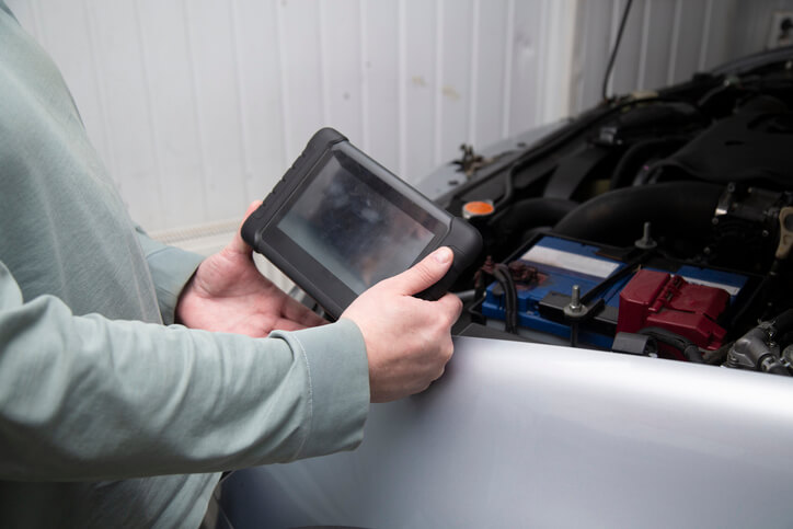 An auto mechanic checking out a vehicle using estimating software after completing auto body estimating training