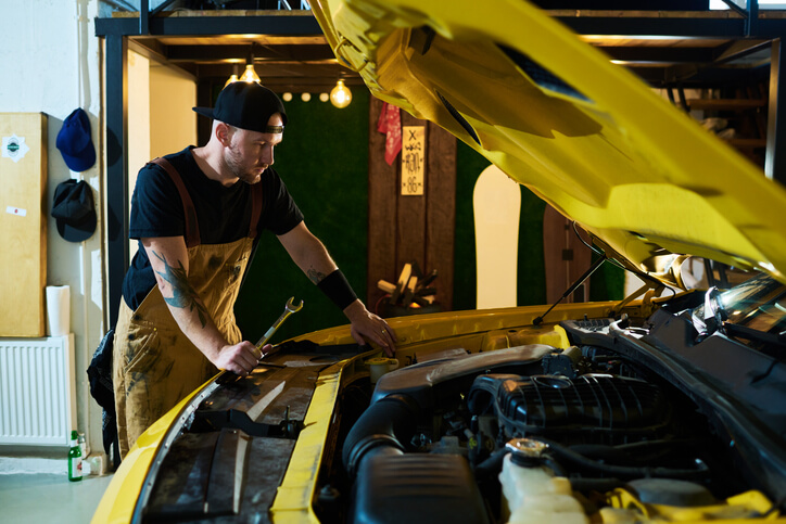 A male hybrid and electric vehicle mechanic working on a vehicle