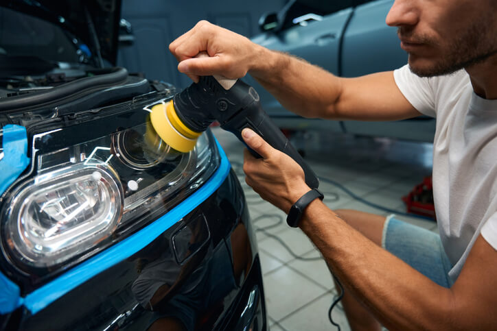 A focused male detailing professional working in an auto repair shop after auto detailing training