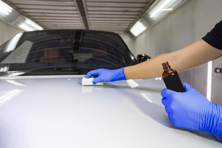 An auto detailing grad applying a ceramic coating to a car