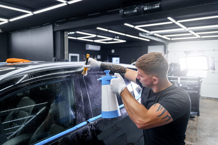 An auto detailing grad adding protective film to a car