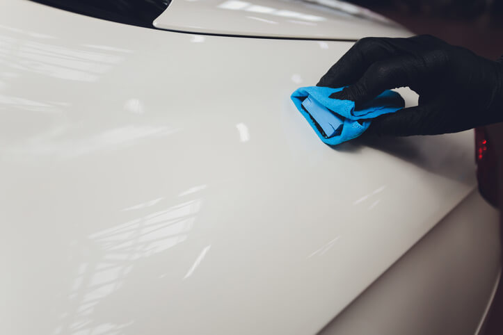 An auto detailing grad applying a ceramic coating to a white car