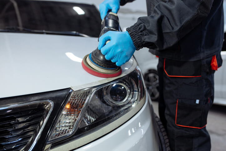 An experienced auto detailer removing scratches from a car’s varnish after auto detailing training