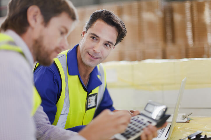 A logistics operations manager discussing with a colleague at a warehouse after dispatch training