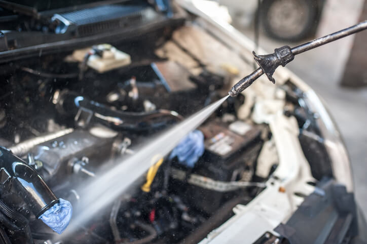 An auto detailer cleaning the engine of a car after auto detailing training