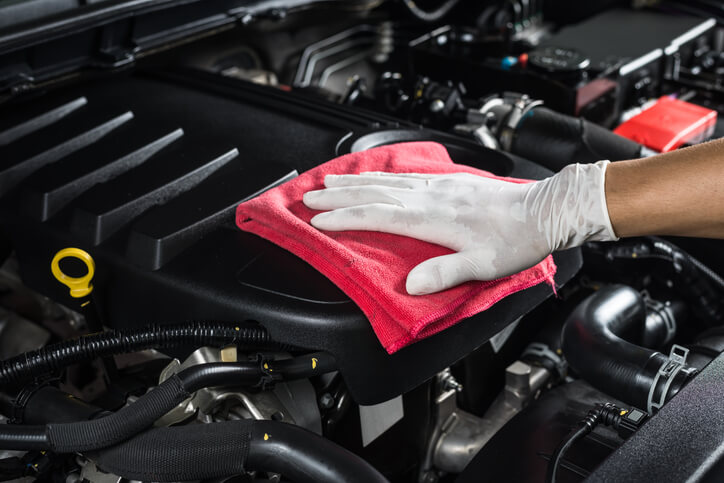 An auto detailing professional wiping down the engine of a vehicle after auto detailing training