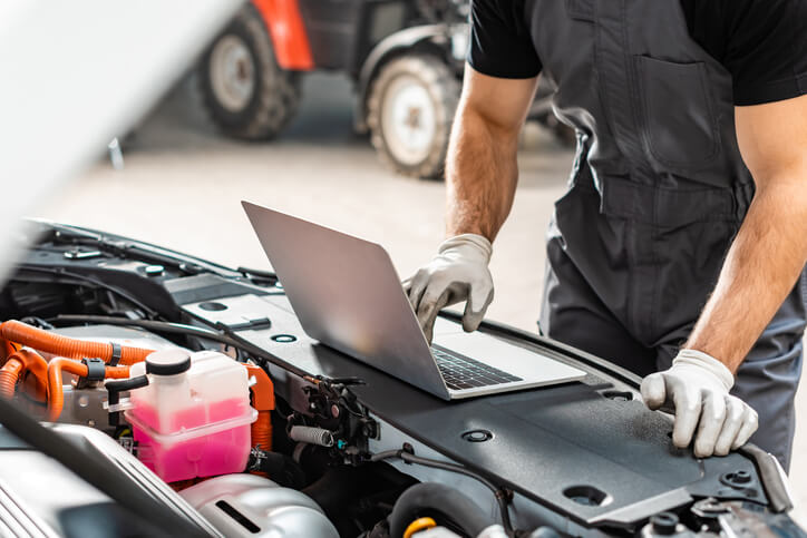 A male auto mechanic using technology to aid his repair efforts after completing auto mechanic training