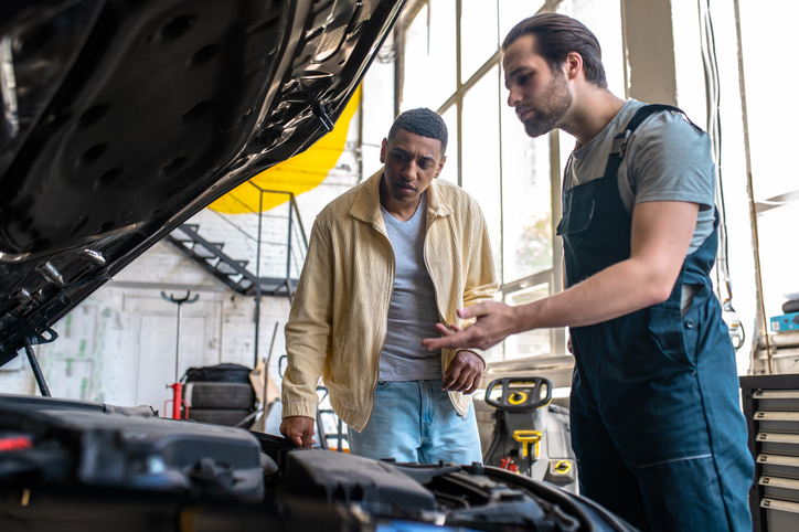 Composed male auto mechanic discussing with a customer after auto mechanic school