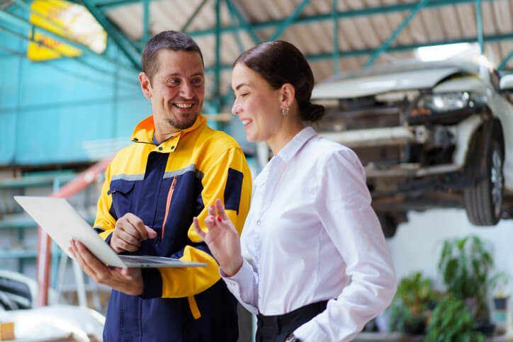 A male mechanic discussing with a female customer in a garage after auto mechanic training