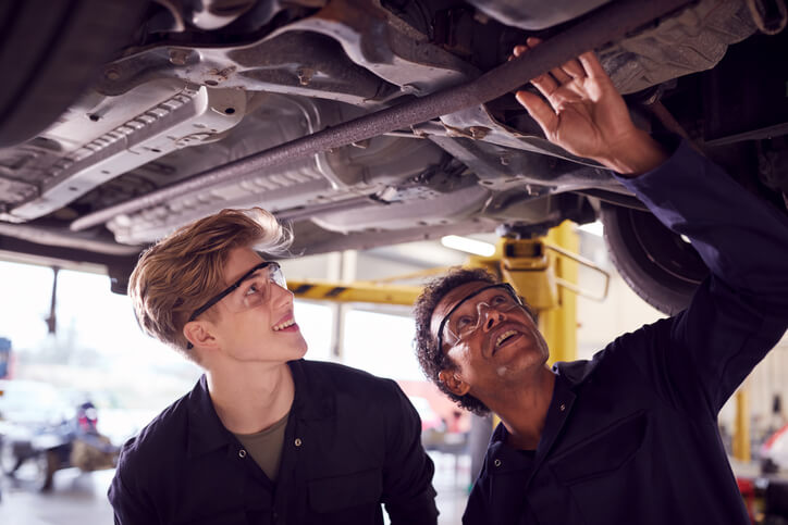 An auto mechanic student receiving instruction from a teacher