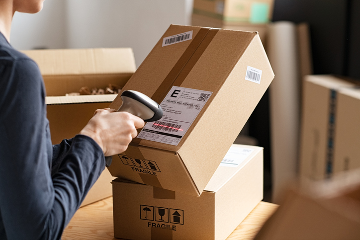 Auto parts clerk scanning the barcode of a package in a warehouse after completing his auto parts training