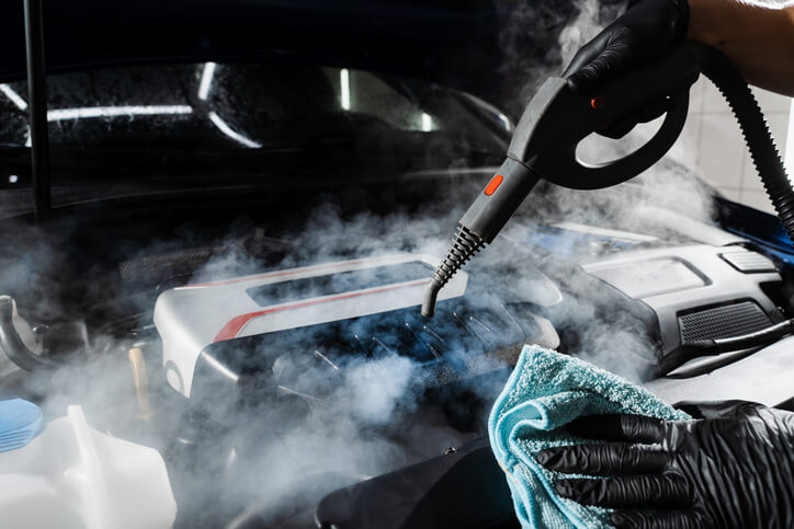 A male auto detailing professional cleaning a car’s interior after auto detailing training