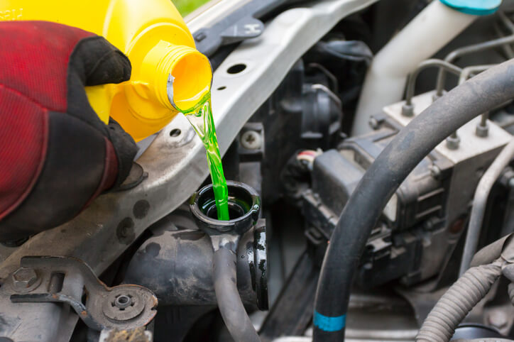 A mechanic filling up coolant as learned in automotive school