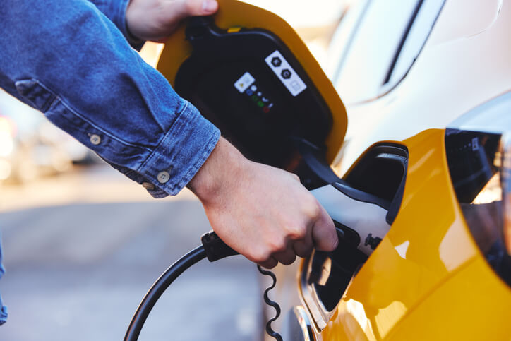 A man using an EV charging station serviced by automotive training grads