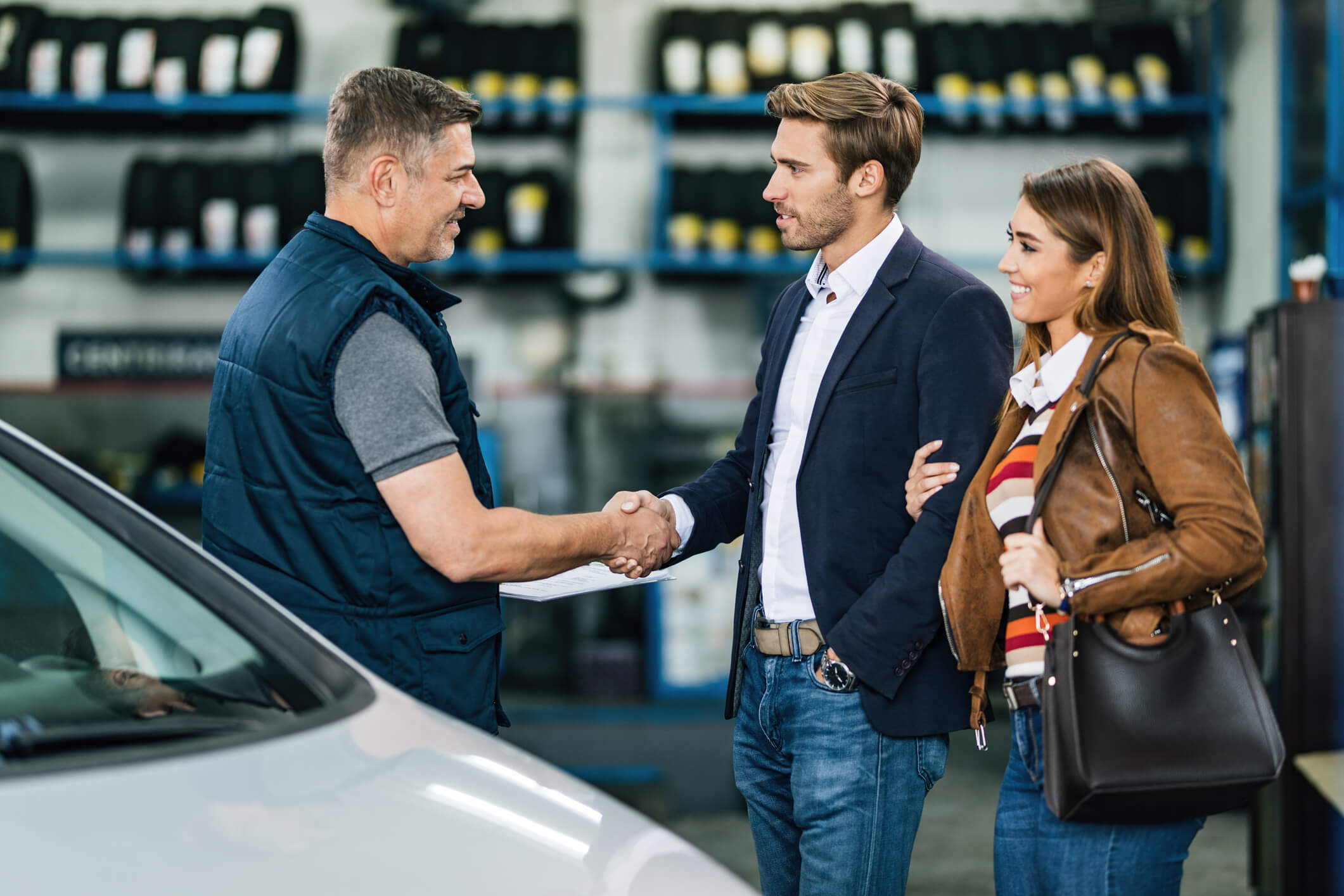 A friendly male auto mechanic interacting with customers after auto mechanic school