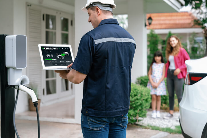 An automotive school grad servicing a home EV charging station