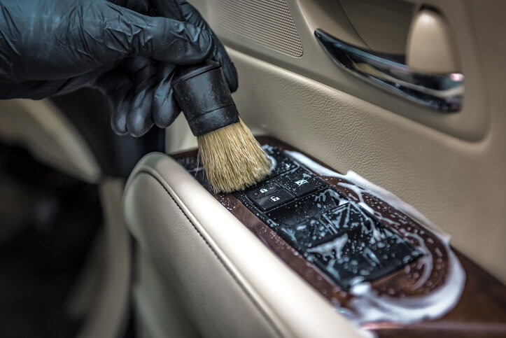 An auto detailing grad washing the interior of a car