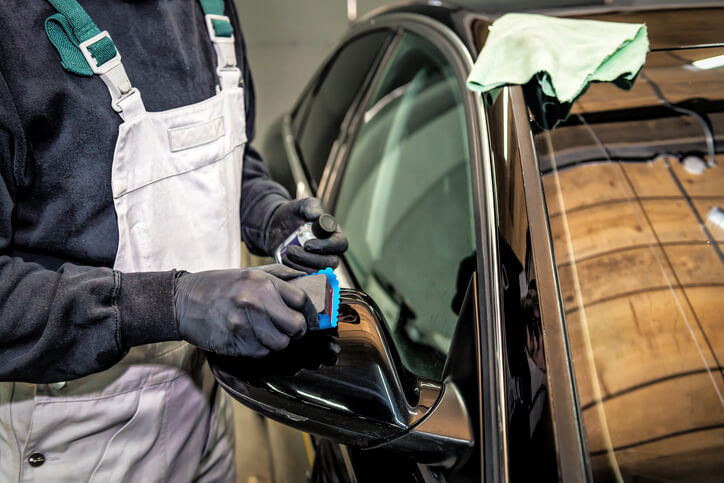 An auto detailing training grad polishing a car with a nano-coating product