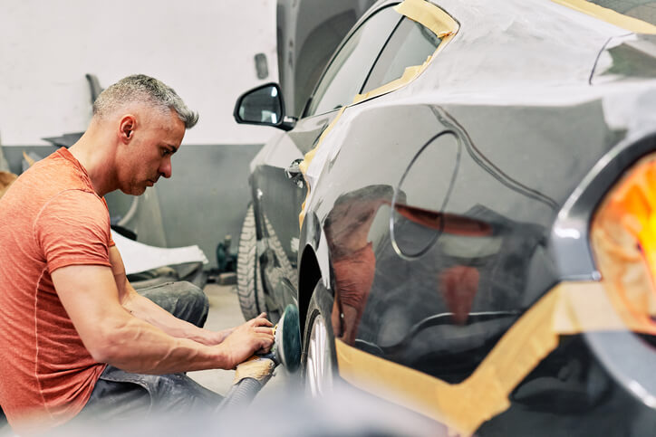 A professional auto detailer working on a vehicle after completing his auto detailing training