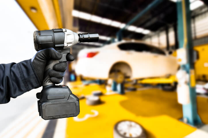 An auto mechanic holding a cordless impact wrench