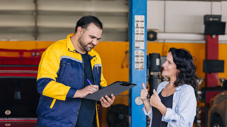 An auto mechanic helping a customer