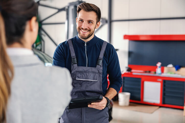 A charming male counter person at an auto parts store greeting a female customer after auto parts training