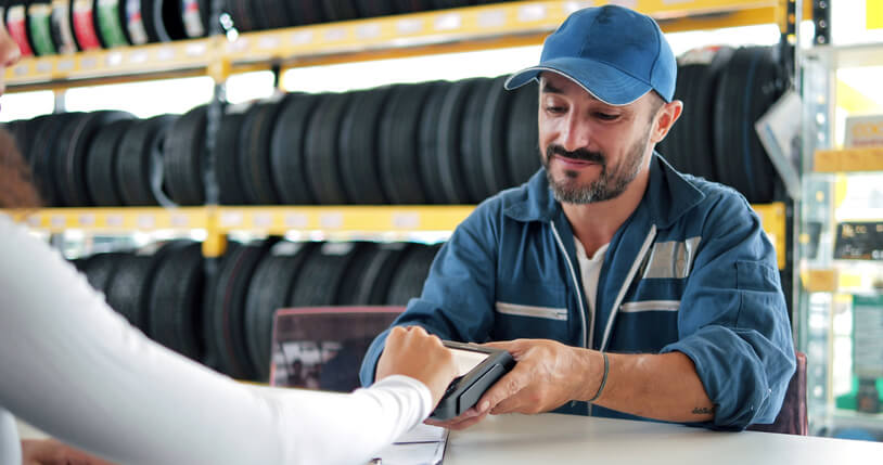 A friendly male counter person at a parts store completes a sales order after auto parts training